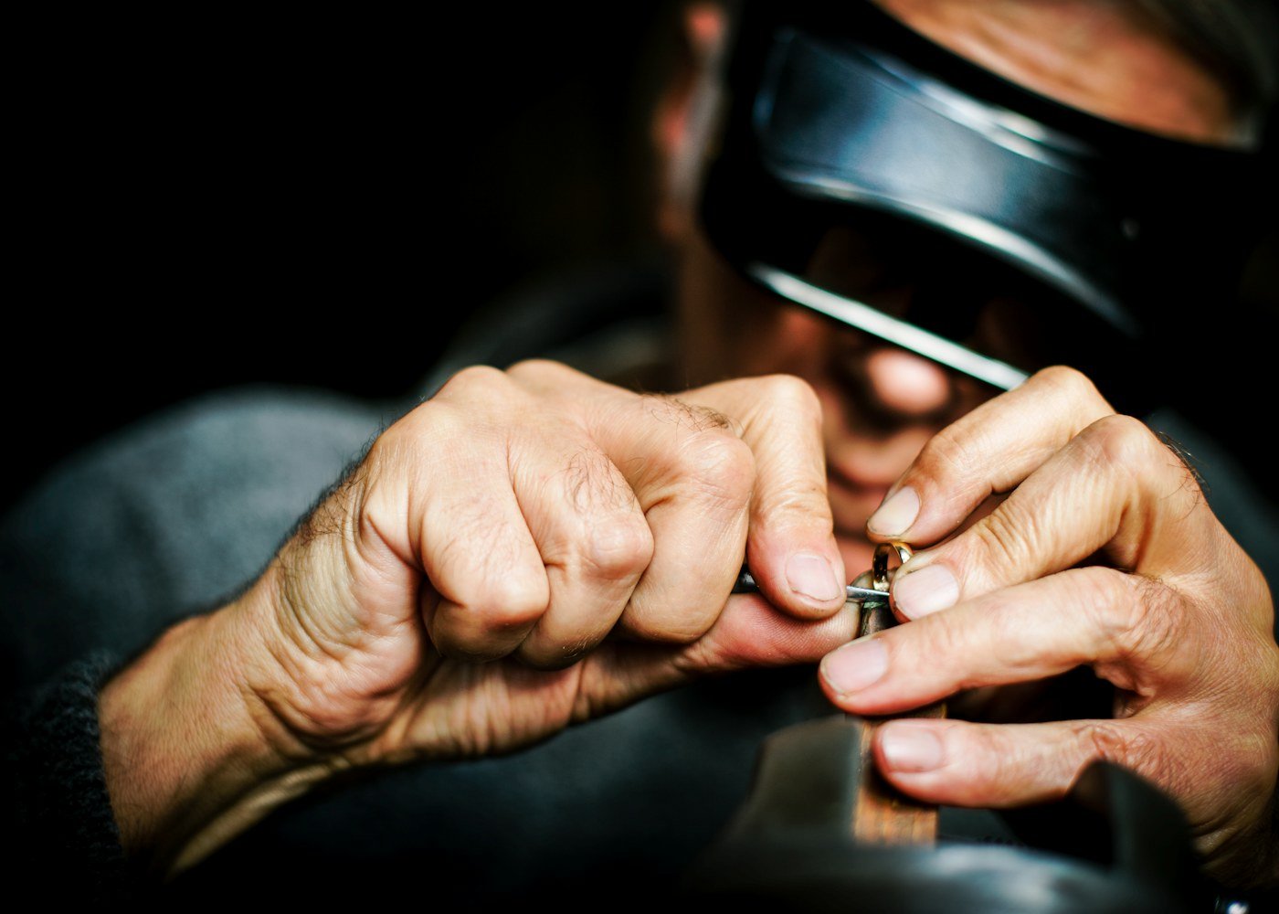 A goldsmith's hands finishing a ring at the bench