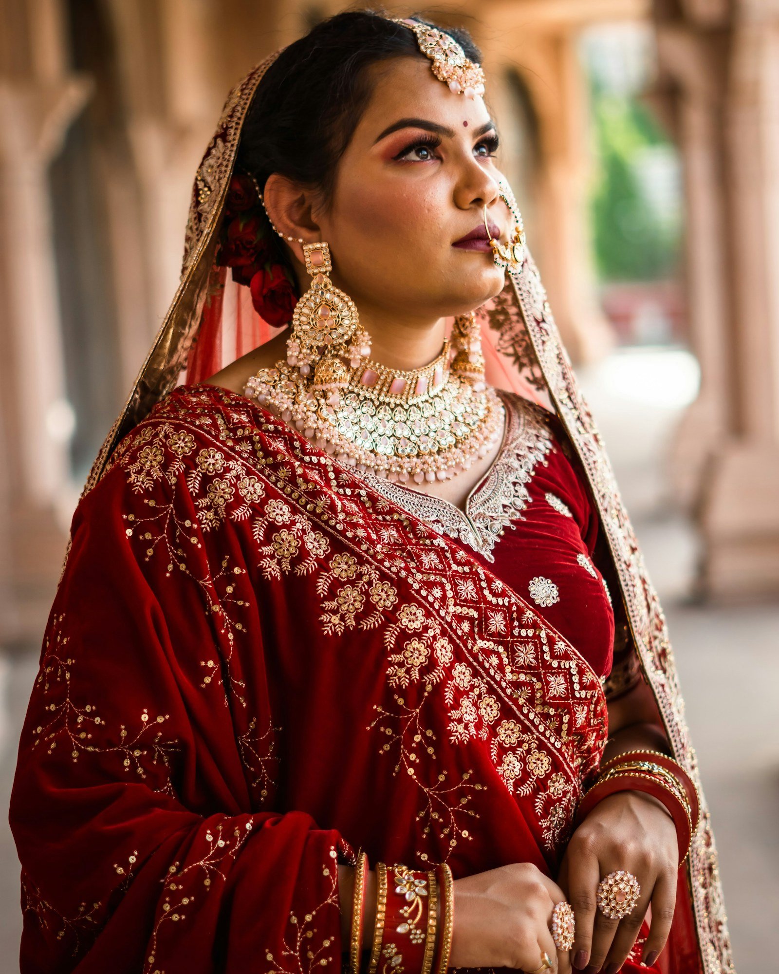 Bride in red velvet wearing a layered gold and pearl necklace set